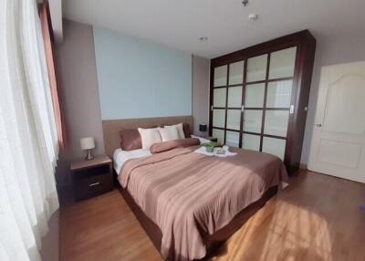 Modern bedroom with wooden flooring, large bed, bedside table, and built-in wardrobe