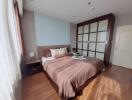 Modern bedroom with wooden flooring, large bed, bedside table, and built-in wardrobe