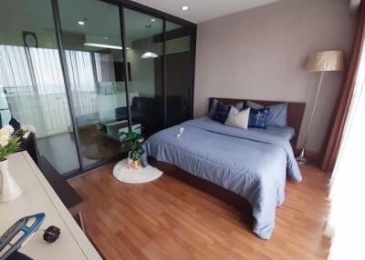 Cozy bedroom with wooden flooring, a large bed, and a glass partition