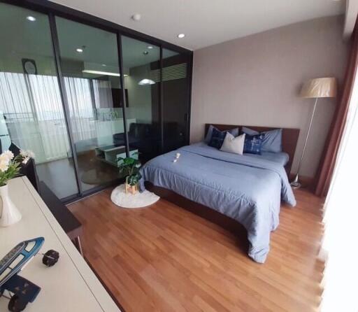 Cozy bedroom with wooden flooring, a large bed, and a glass partition