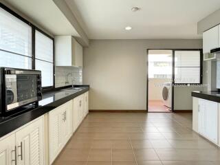 Spacious modern kitchen with black countertops, white cabinets, and appliances