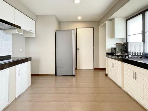 Modern kitchen with white cabinets, stainless steel appliances, and large window