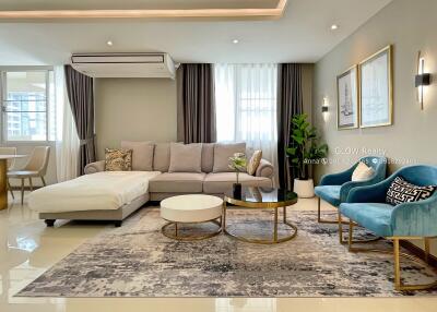 Modern furnished living room with a sectional sofa, chairs, coffee tables, and decor