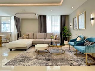 Modern furnished living room with a sectional sofa, chairs, coffee tables, and decor