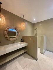 Modern bathroom with minimalist design featuring a large vanity mirror and pendant lights