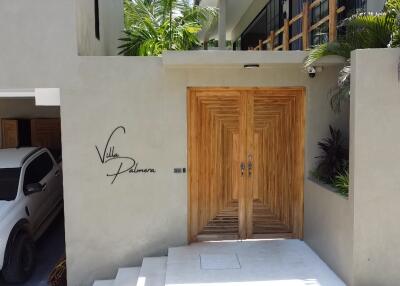 Stylish wooden door entryway of Villa Palma with covered parking space