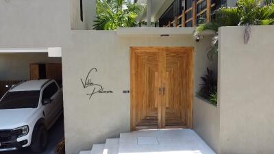 Stylish wooden door entryway of Villa Palma with covered parking space