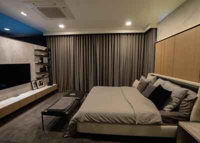 Modern bedroom with large bed, wall-mounted TV, and sleek furnishings
