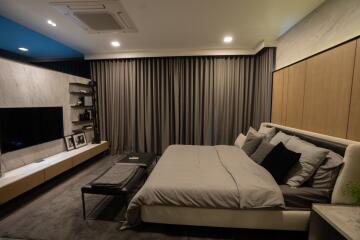 Modern bedroom with large bed, wall-mounted TV, and sleek furnishings