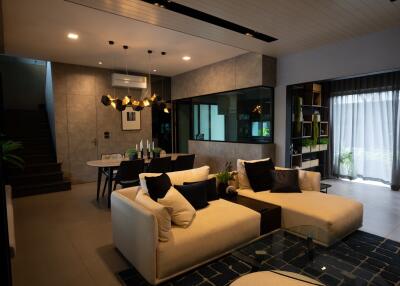 Stylish modern living room with a sectional sofa, dining area, glass table, and contemporary lighting