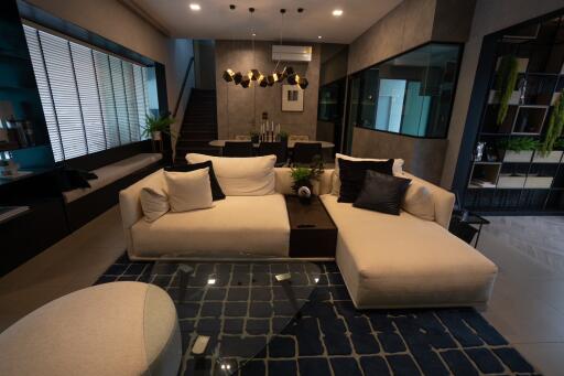 Modern living room with white sectional sofa, glass coffee table, and dark accents