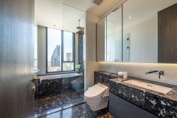 Modern bathroom with marble flooring, glass shower, and city view