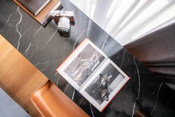 A study desk with a book, glasses, a camera, and a notebook