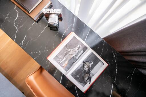 A study desk with a book, glasses, a camera, and a notebook