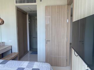 Modern bedroom with wooden door, large wardrobe, and TV