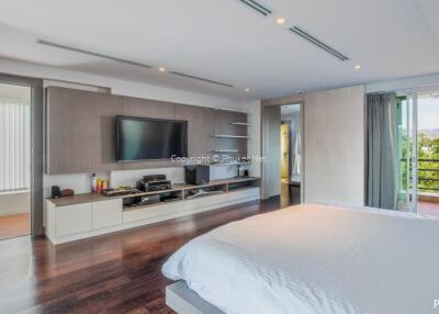 Spacious modern bedroom with a large TV and balcony