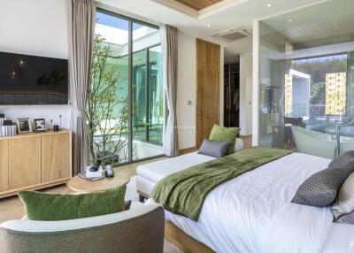 Modern bedroom with large windows, green accents, and a view of outdoor patio