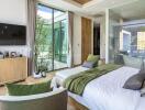 Modern bedroom with large windows, green accents, and a view of outdoor patio