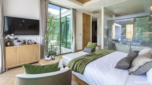 Modern bedroom with large windows, green accents, and a view of outdoor patio