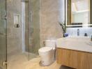 Modern bathroom with glass-enclosed shower, toilet, and sink with a mirror