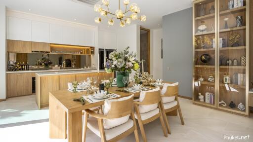 Modern dining room with wooden table and chairs, adjacent to open kitchen