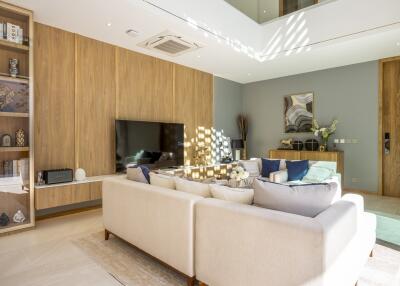 Modern living room with wooden paneling, built-in shelves, and a large flat-screen TV
