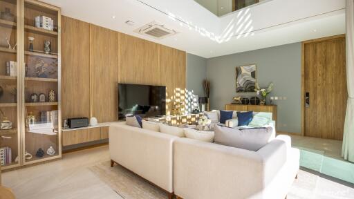 Modern living room with wooden paneling, built-in shelves, and a large flat-screen TV
