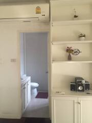 hallway leading to bathroom with small cabinets and air conditioning unit