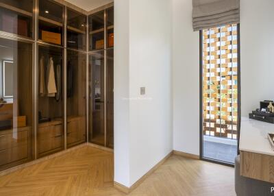 Modern dressing room with glass wardrobes and wooden flooring