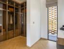 Modern dressing room with glass wardrobes and wooden flooring