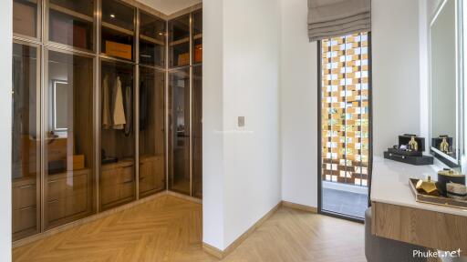 Modern dressing room with glass wardrobes and wooden flooring