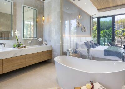 Spacious and luxurious bedroom with an open bathroom featuring a modern freestanding bathtub, large vanity with dual sinks, and large windows overlooking a lush garden.