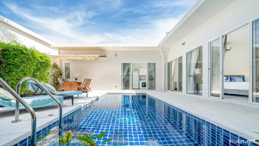 Modern poolside patio with outdoor furniture and garden