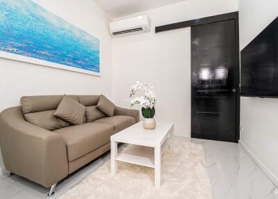 modern living room with sofa, coffee table, wall-mounted TV, and air conditioner