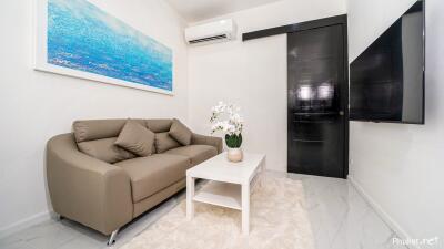 modern living room with sofa, coffee table, wall-mounted TV, and air conditioner