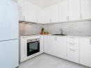 Modern white kitchen with appliances and marble backsplash