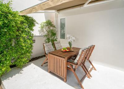 Outdoor patio with wooden dining furniture and green plants