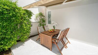 Outdoor patio with wooden dining furniture and green plants