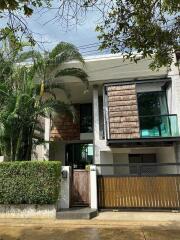 Front exterior view of a modern house with trees and greenery