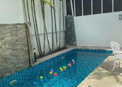 Outdoor swimming pool with colorful balls and patio area