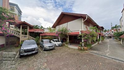 Exterior view of a residential building with parked cars and greenery