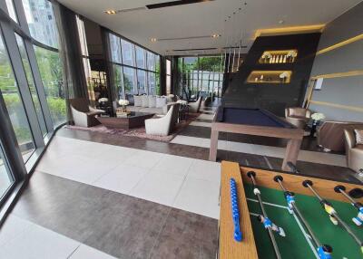 Spacious and modern recreational area with large windows, a seating area, a pool table, and a foosball table.