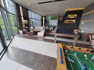 Spacious and modern recreational area with large windows, a seating area, a pool table, and a foosball table.