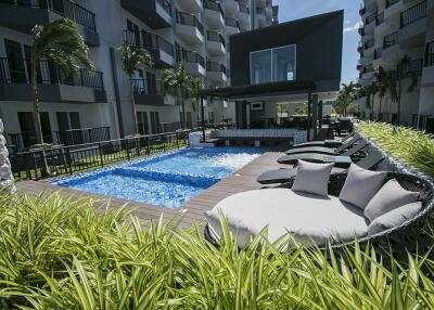 Modern outdoor communal pool area with lounge chairs and greenery.