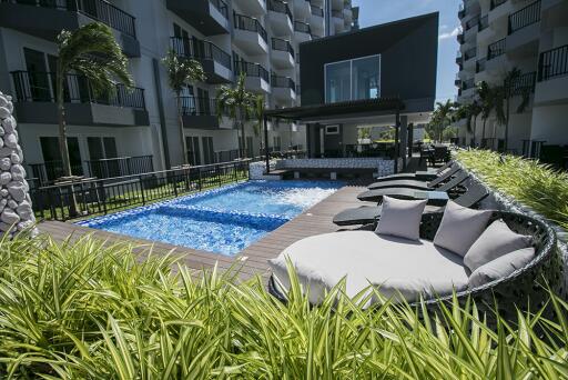 Modern outdoor communal pool area with lounge chairs and greenery.