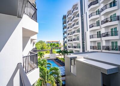 View from a balcony of an apartment building overlooking a pool and greenery