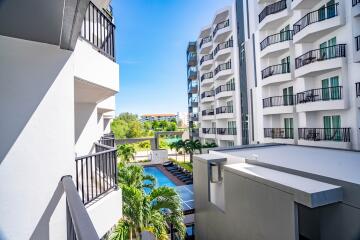 View from a balcony of an apartment building overlooking a pool and greenery