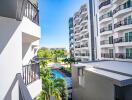 View from a balcony of an apartment building overlooking a pool and greenery