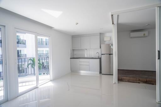 A bright and modern open living area with a kitchenette and large windows.