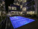 Outdoor pool area at night with illuminated pool and adjacent lounge seating